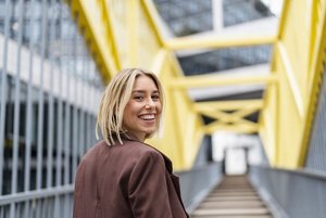 Woman with a choppy blonde balayage bob standing on a yellow bridge
